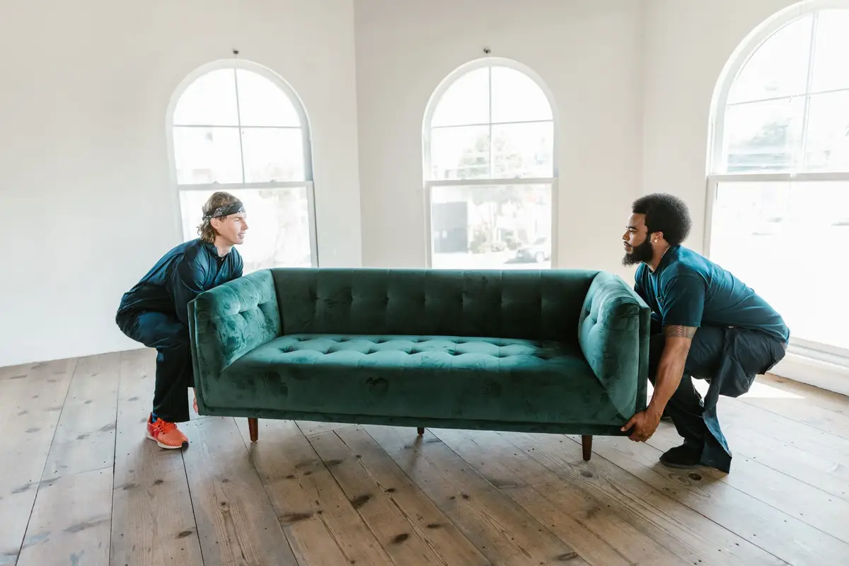 Two movers carrying a sofa through a living room